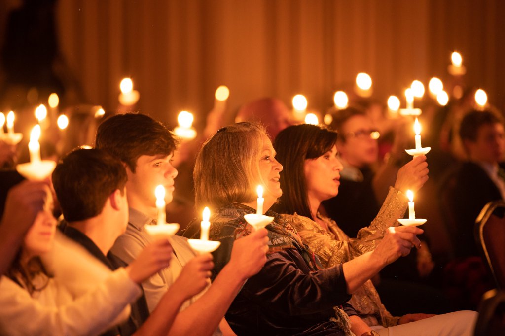 people holding lit candles up and singing.